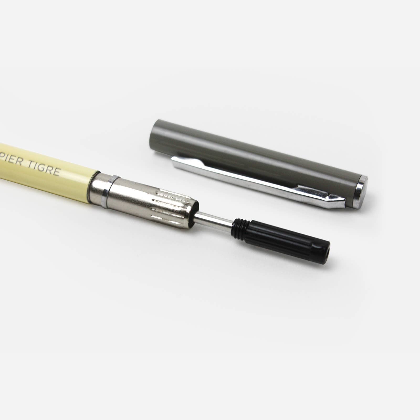 Pen with beige body and silver accents with a black ink refill on a white background