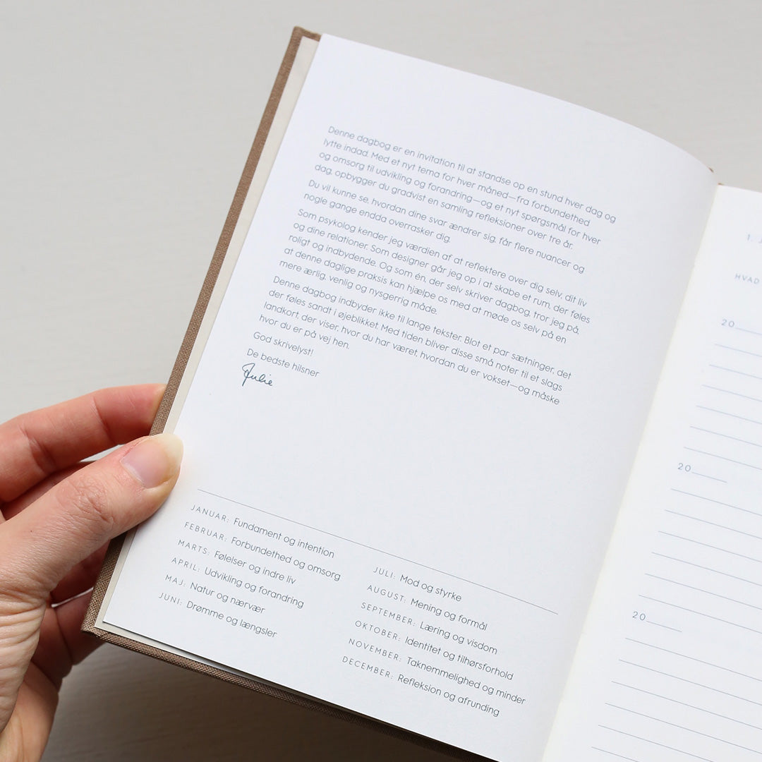 Hand holding an open book with text on a plain background