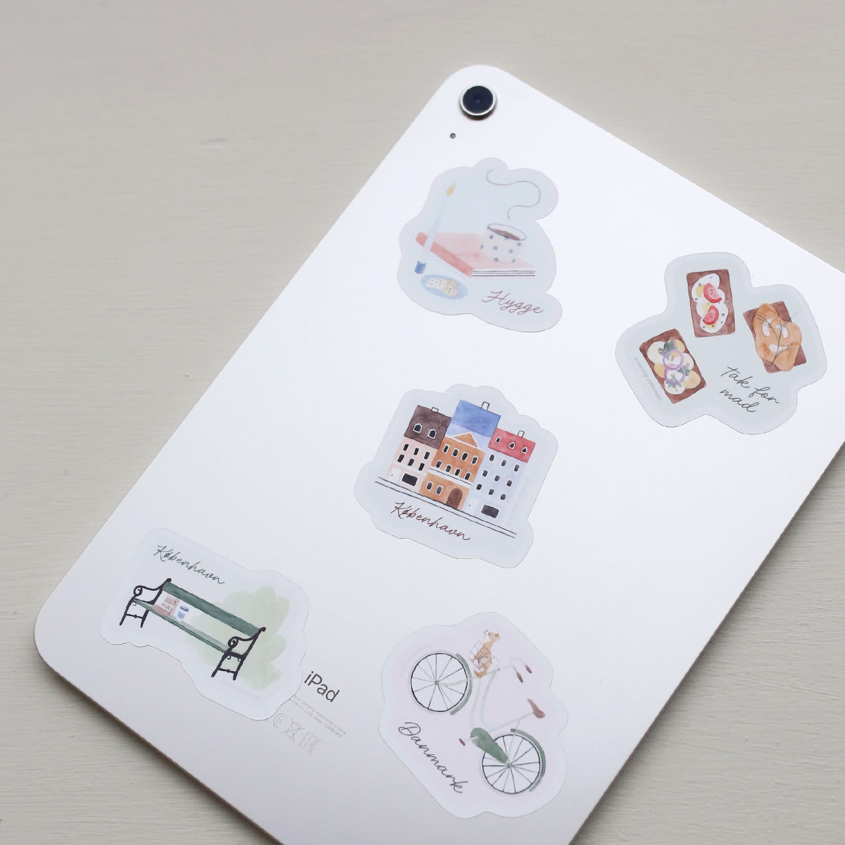 Tablet decorated with Danish illustrated vinyl stickers on a light gray background