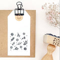 Floral stamp on a white background with a wooden handle and a small plant.