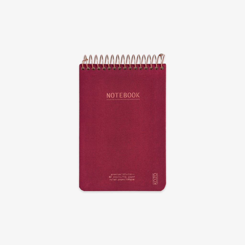 Red notebook with spiral binding on a white background