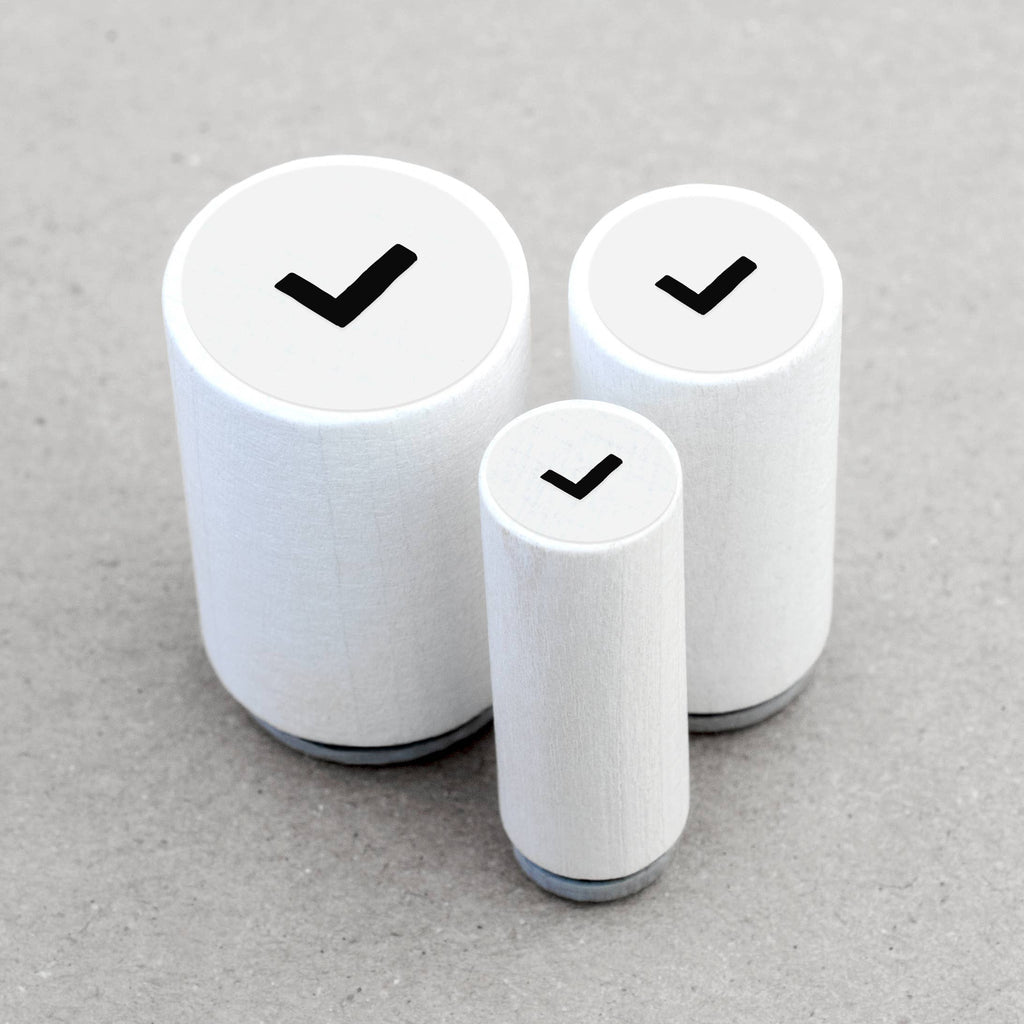 Three wooden rubber stamps with black check marks on a gray background
