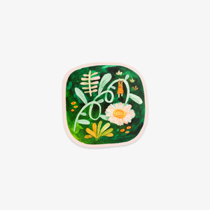 A square sticker with rounded corners featuring a colorful watercolor-style botanical illustration on a dark green background, with a white daisy, green leaves, yellow accents, and a light pink border, shown on a plain light gray background.