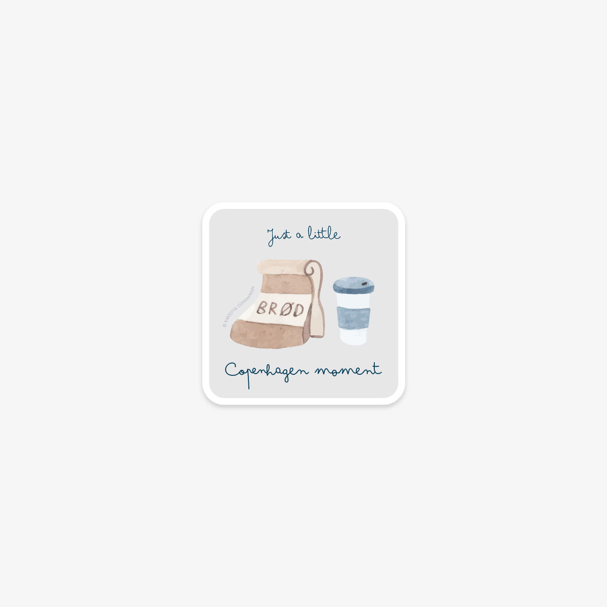 Vinyl sticker with bread and coffee design and the text 'just a little copenhagen moment' on a white background