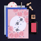 Card with turtle design and floral patterns, surrounded by stamps and ink pad on a dark background