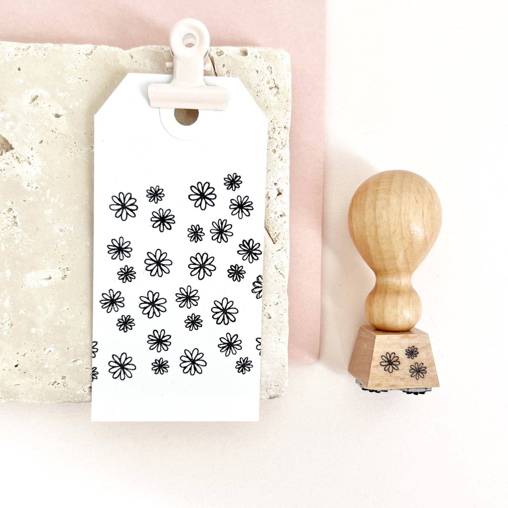 White card with black floral patterns and a wooden stamp on a light pink background